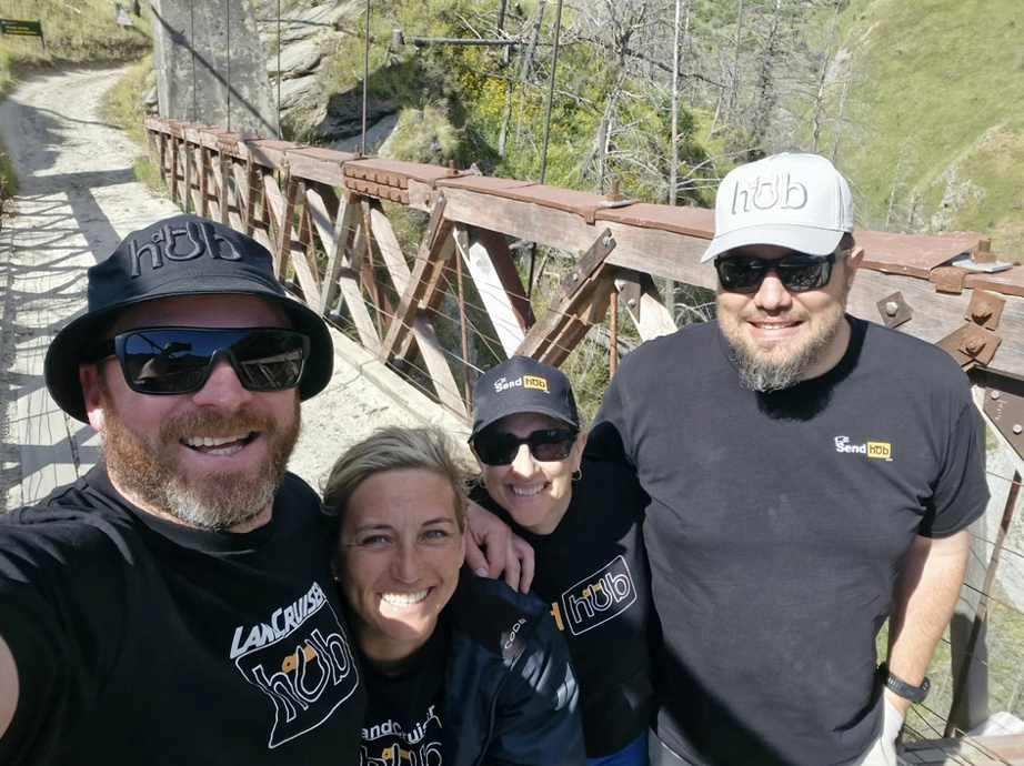 Full Send Hub 4WD caps worn by Kiwi team on a New Zealand off-road bridge, shop the hats collection now.